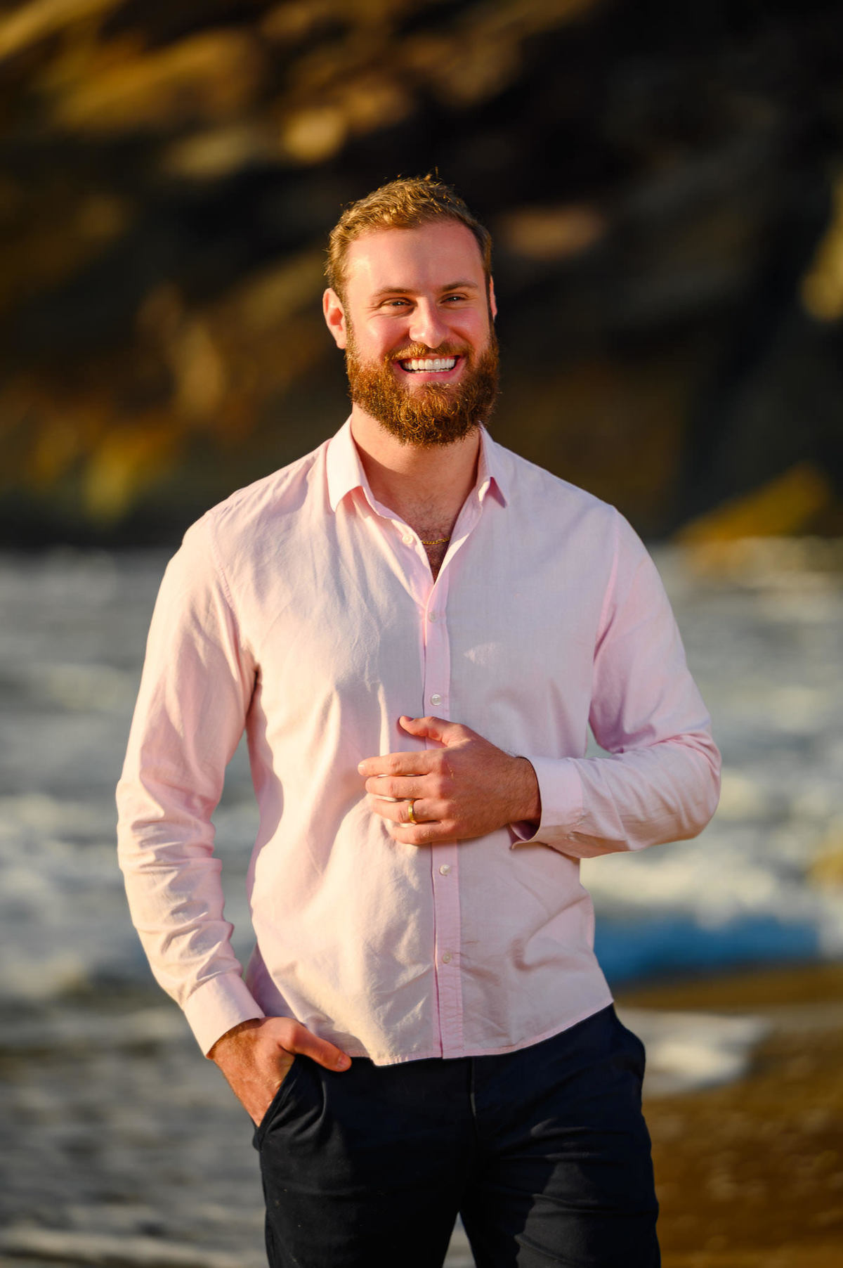 Retrato individual do noivo sorrindo com o mar ao fundo em ensaio pré-casamento