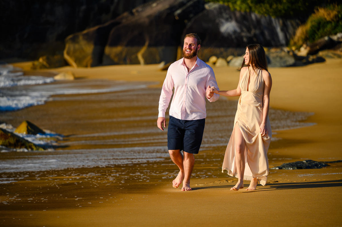Casal caminhando pela areia de mãos dadas na Praia do Estaleirinho