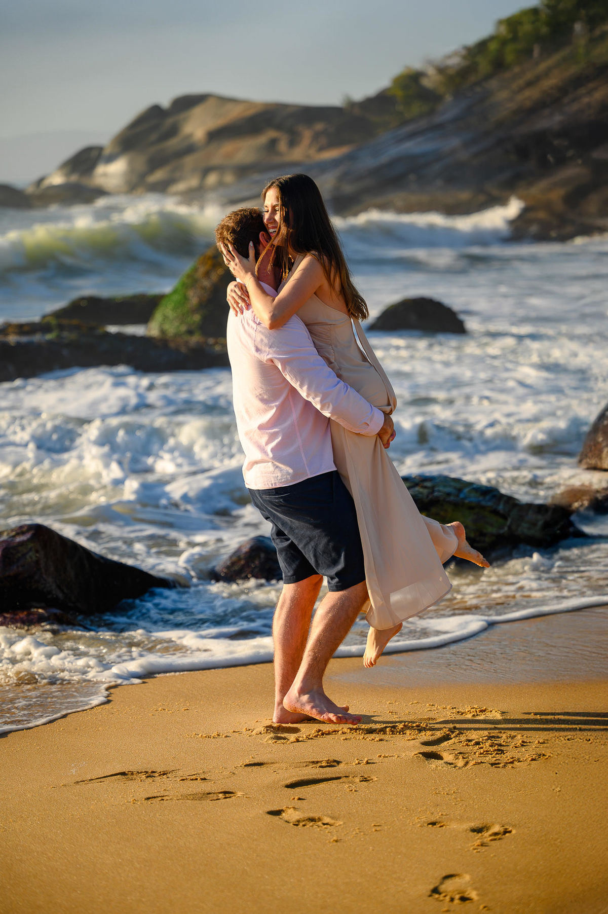 Casal girando na areia com o mar ao fundo em ensaio pré-wedding em Balneário Camboriú