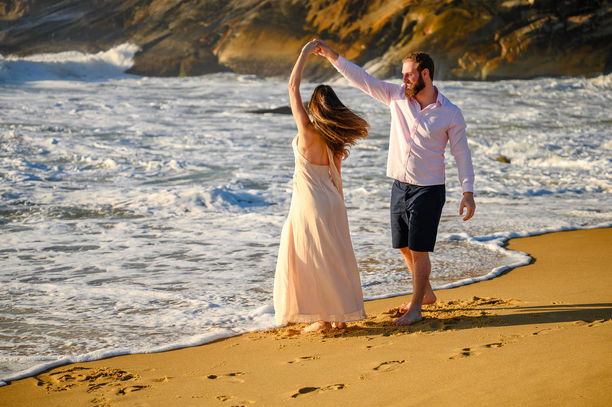 Casal girando na areia com o mar ao fundo em ensaio pré-wedding em Balneário Camboriú