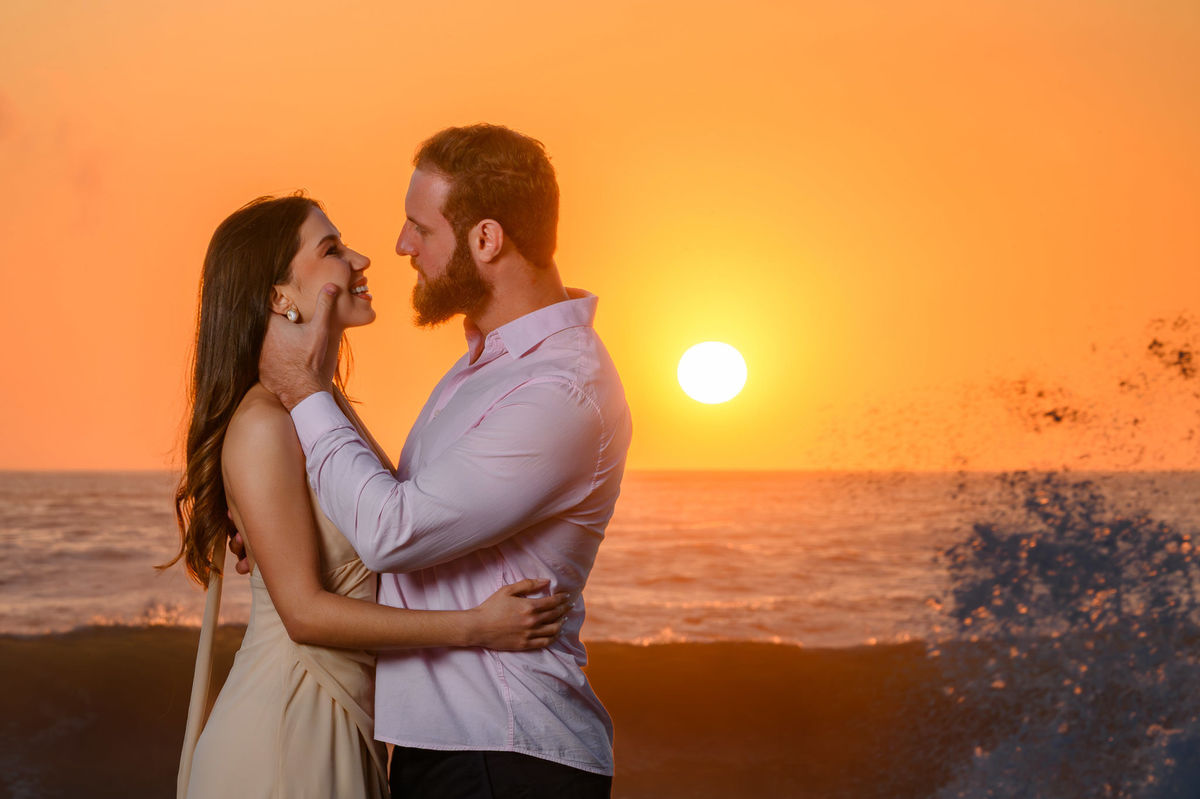 Casal se olhando de frente com ondas ao fundo durante ensaio pré-wedding em Balneário Camboriú