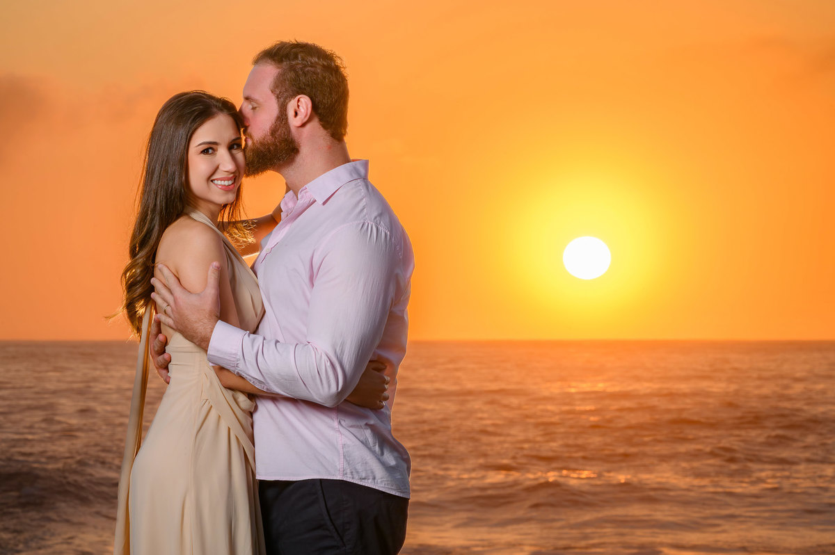 Fotografia de casal abraçado na praia com luz dourada do nascer do sol em Santa Catarina