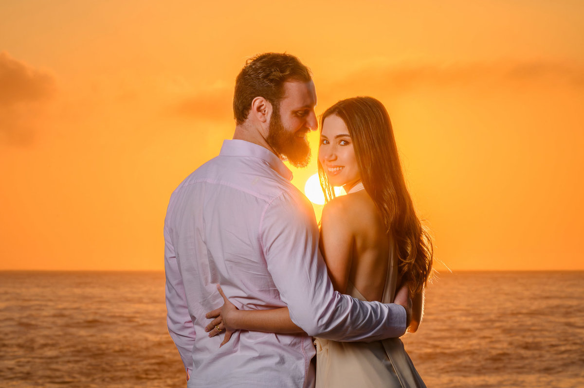 Fotografia de casal abraçado na praia com luz dourada do nascer do sol em Santa Catarina