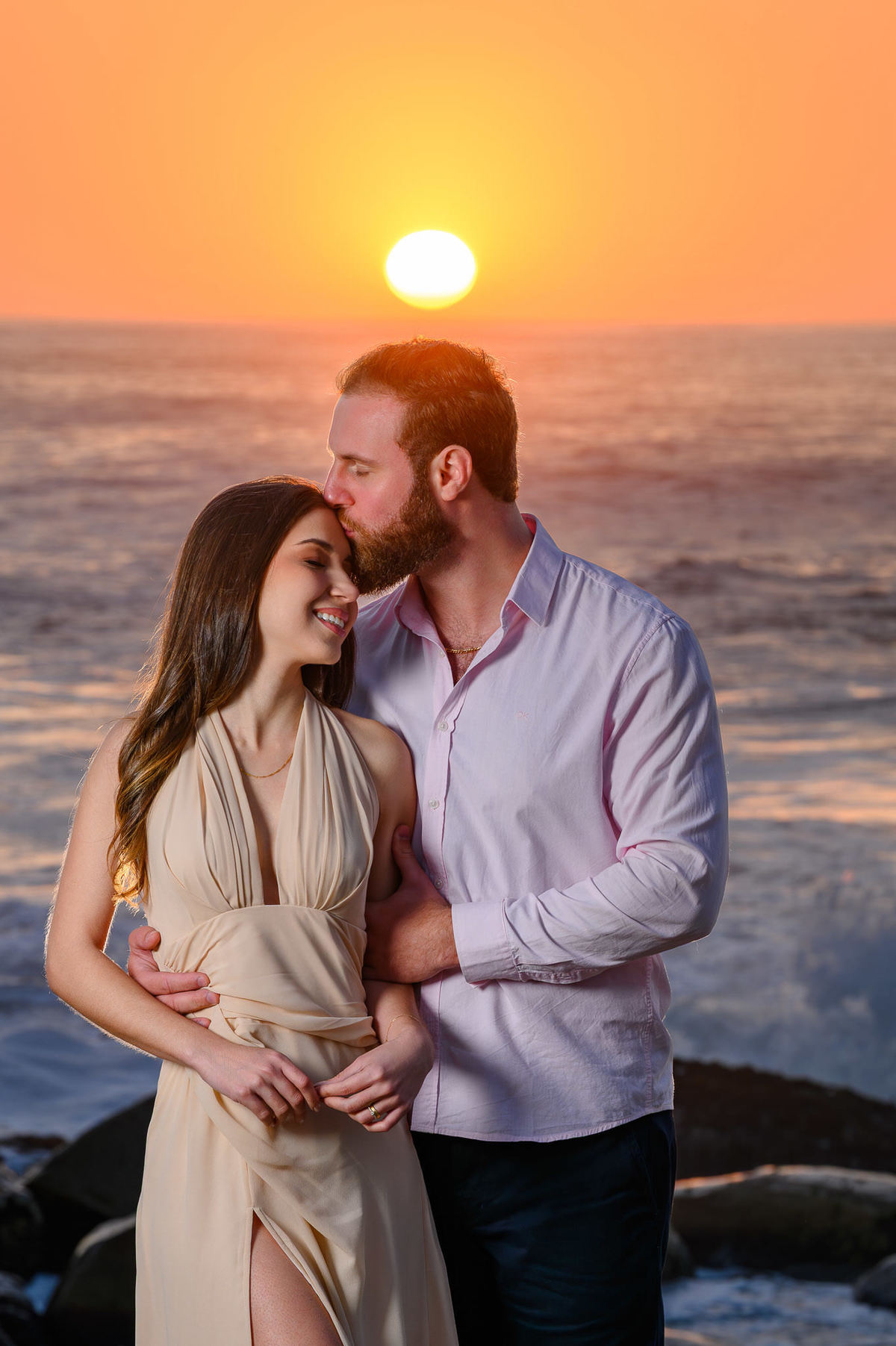 Ensaio pré-wedding com casal se beijando com o sol surgindo no horizonte em Balneário Camboriú