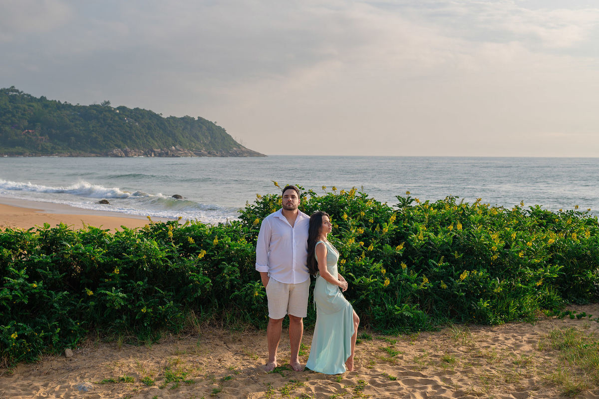 ensaio fotográfico de casal na praia do estaleirinho balneário camboriú com vegetação e mar ao fundo