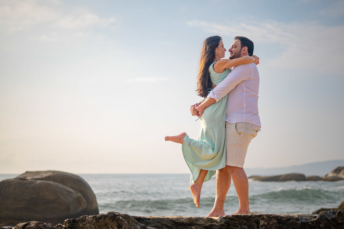ensaio pré wedding balneário camboriú casal sorrindo entre as pedras da praia do estaleirinho