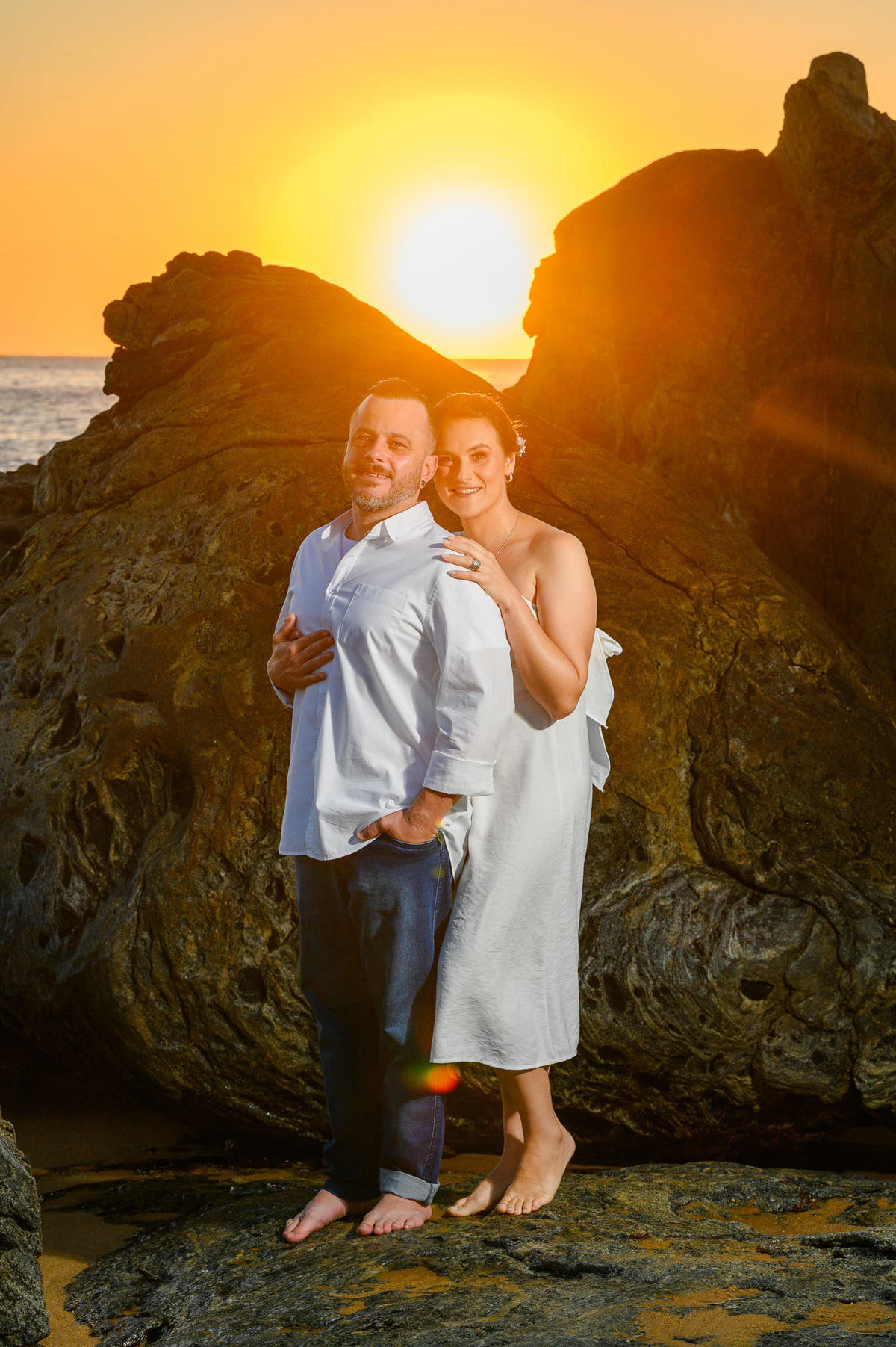 casal fotografado nas pedras da praia ao amanhece