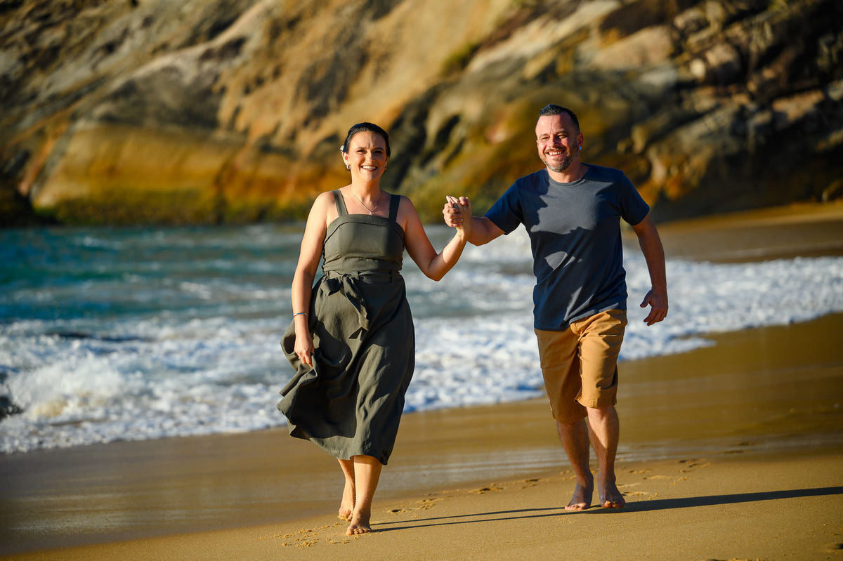 casal caminhando na areia durante ensaio fotográfico