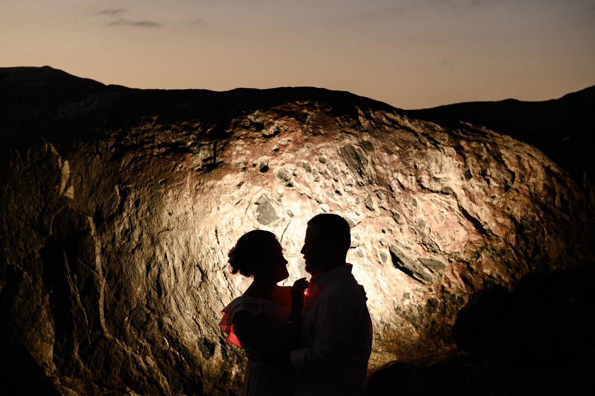 casal fotografado nas pedras da praia ao amanhece