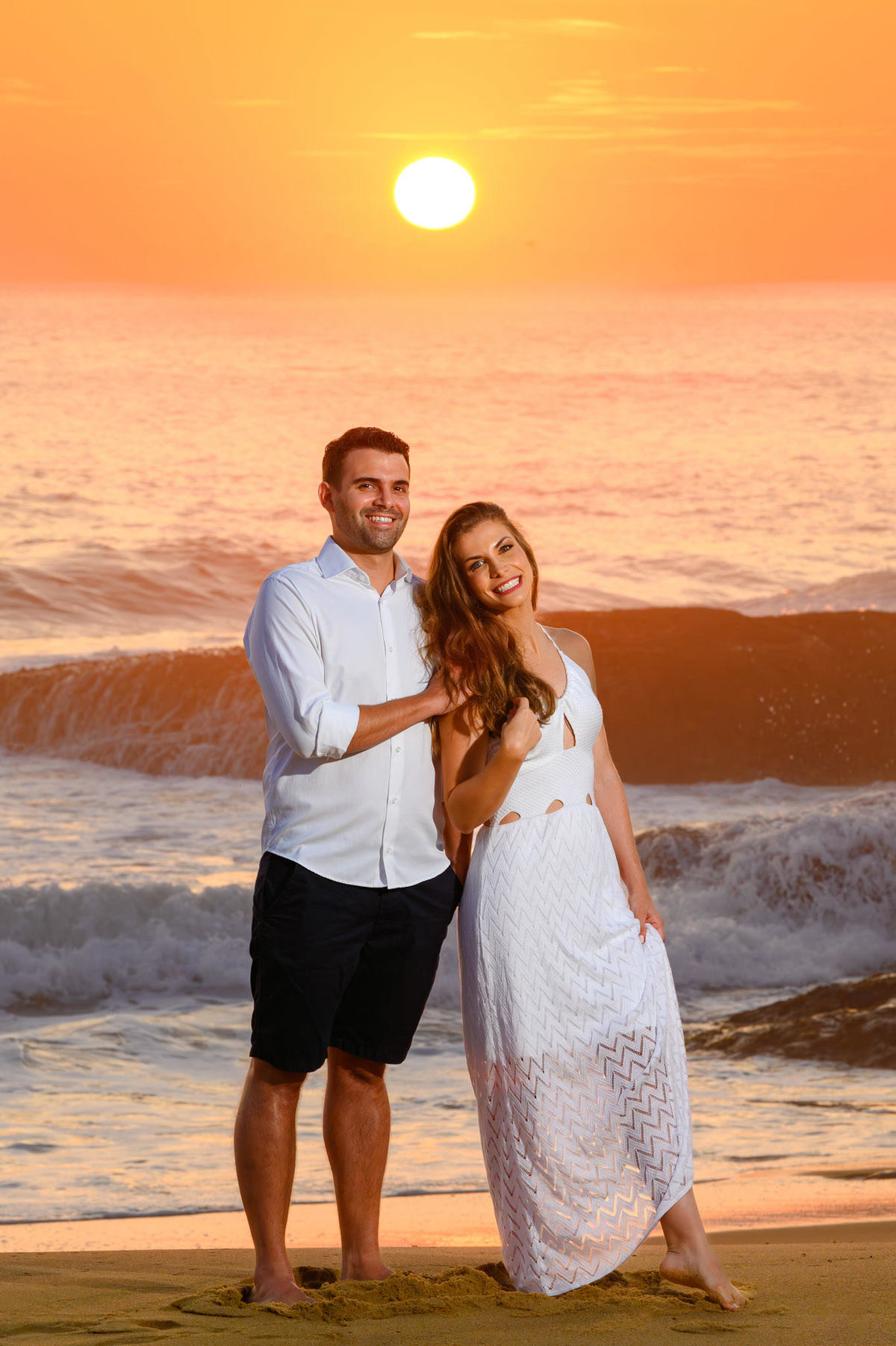 Close do casal abraçado com céu alaranjado do amanhecer na praia em Balneário Camboriú – SC