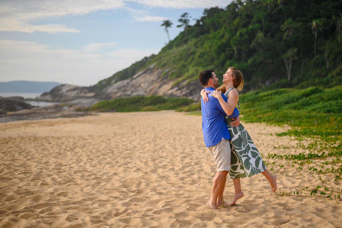Casal se abraçando com sorriso espontâneo durante ensaio pré-wedding na praia em Santa Catarina