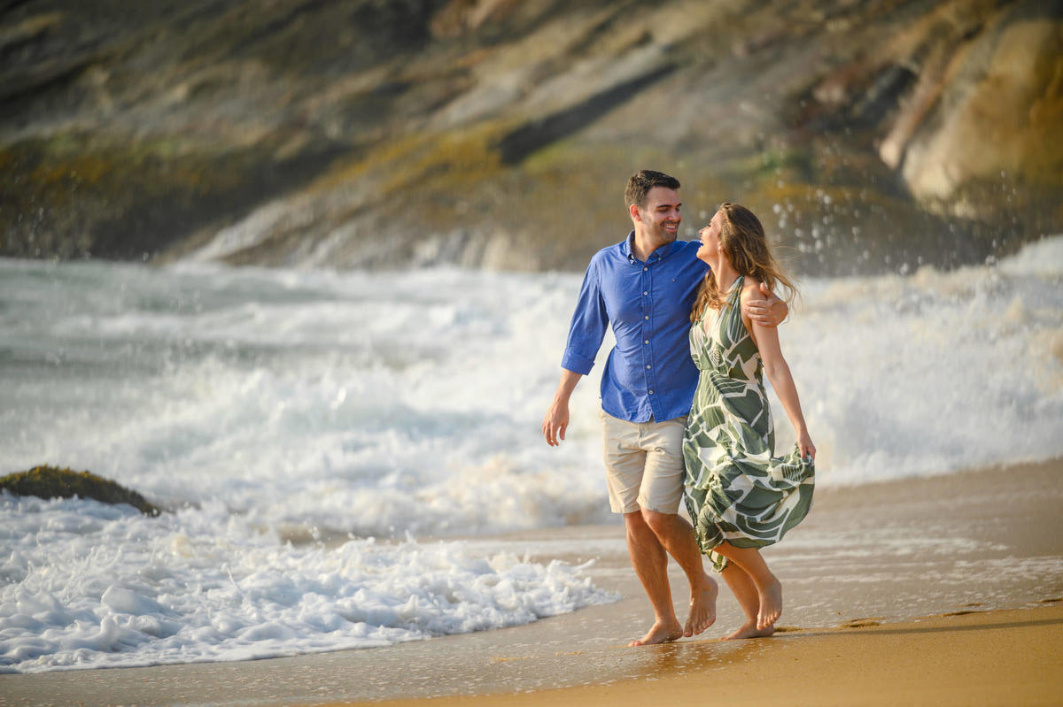 Casal abraçado com ondas quebrando ao fundo em ensaio de casal na praia em Santa Catarina