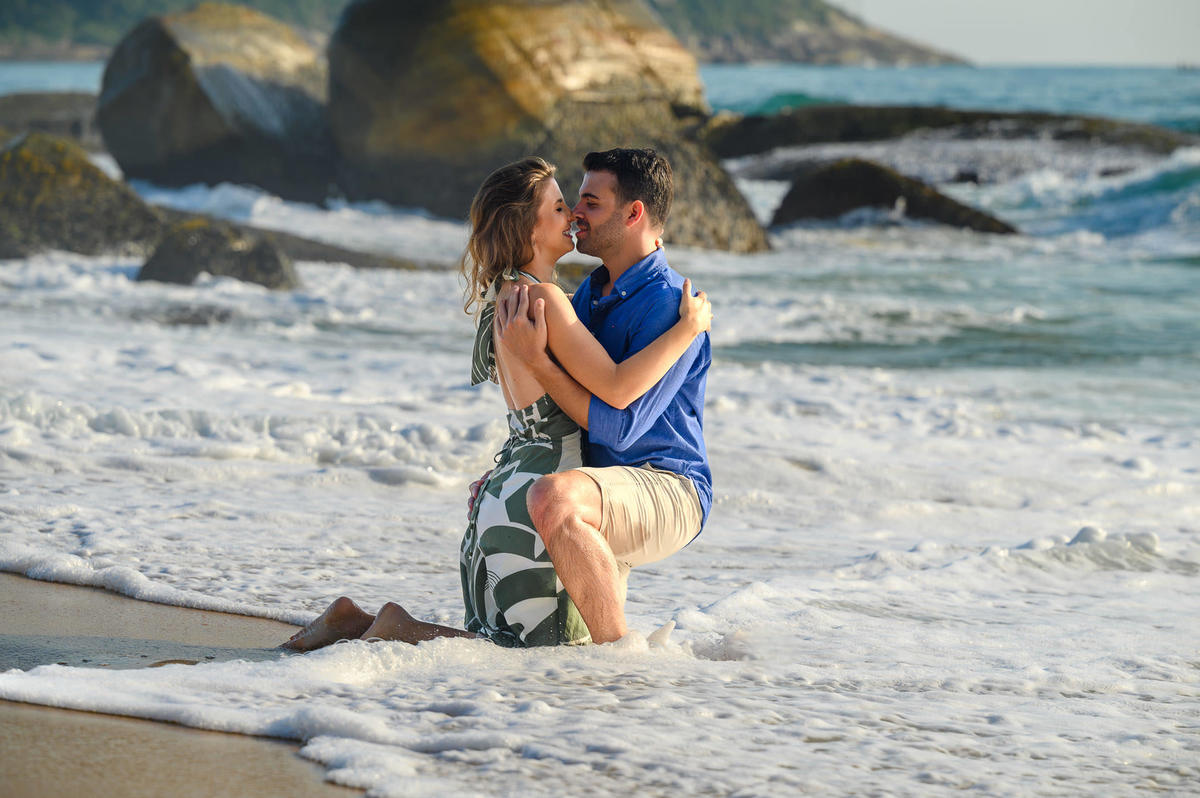 Casal se beijando enquanto ondas molham a areia durante ensaio pré-wedding em Balneário Camboriú – SC
