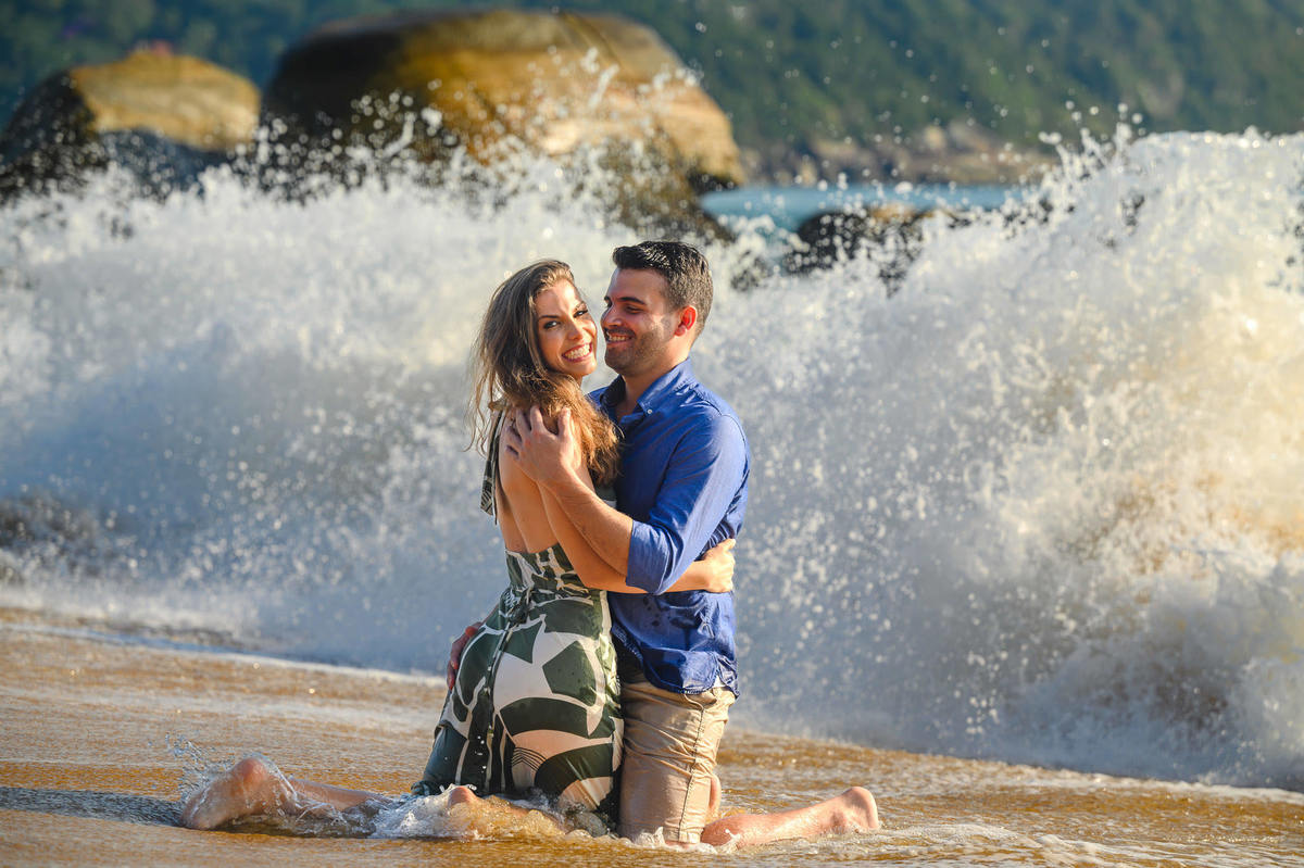 Casal se beijando enquanto ondas molham a areia durante ensaio pré-wedding em Balneário Camboriú – SC