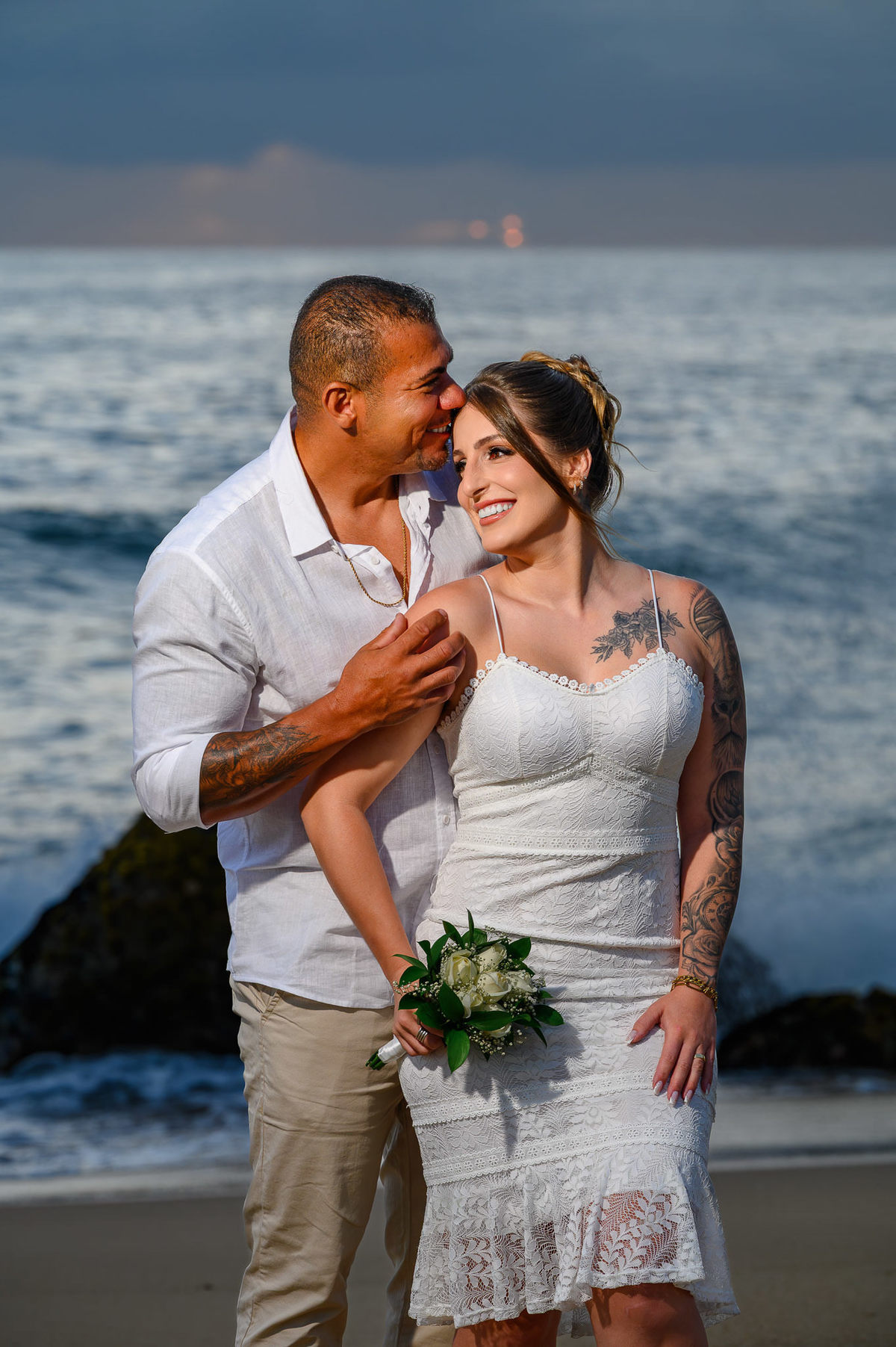 Casal sorrindo na beira do mar durante ensaio fotográfico de casal ao amanhecer na praia do Estaleirinho em Balneário Camboriú