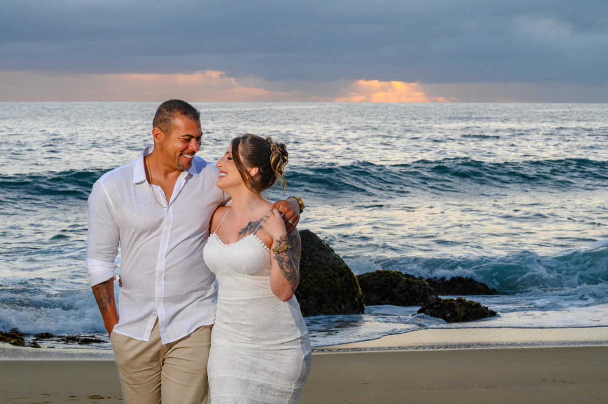 Silhueta de casal se beijando ao amanhecer na praia, ensaio romântico com céu claro em Balneário Camboriú