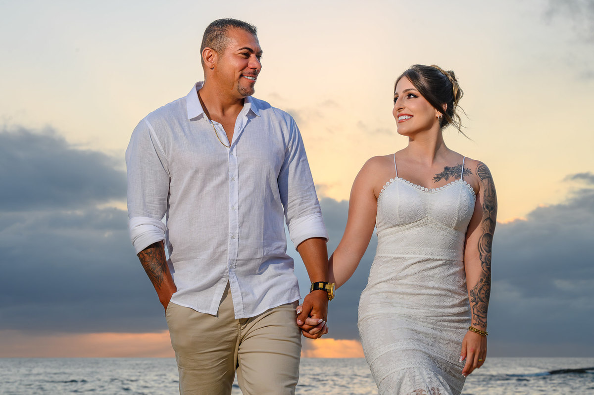 Casal caminhando de frente para o mar durante ensaio fotográfico ao amanhecer na praia do Estaleirinho em Balneário Camboriú