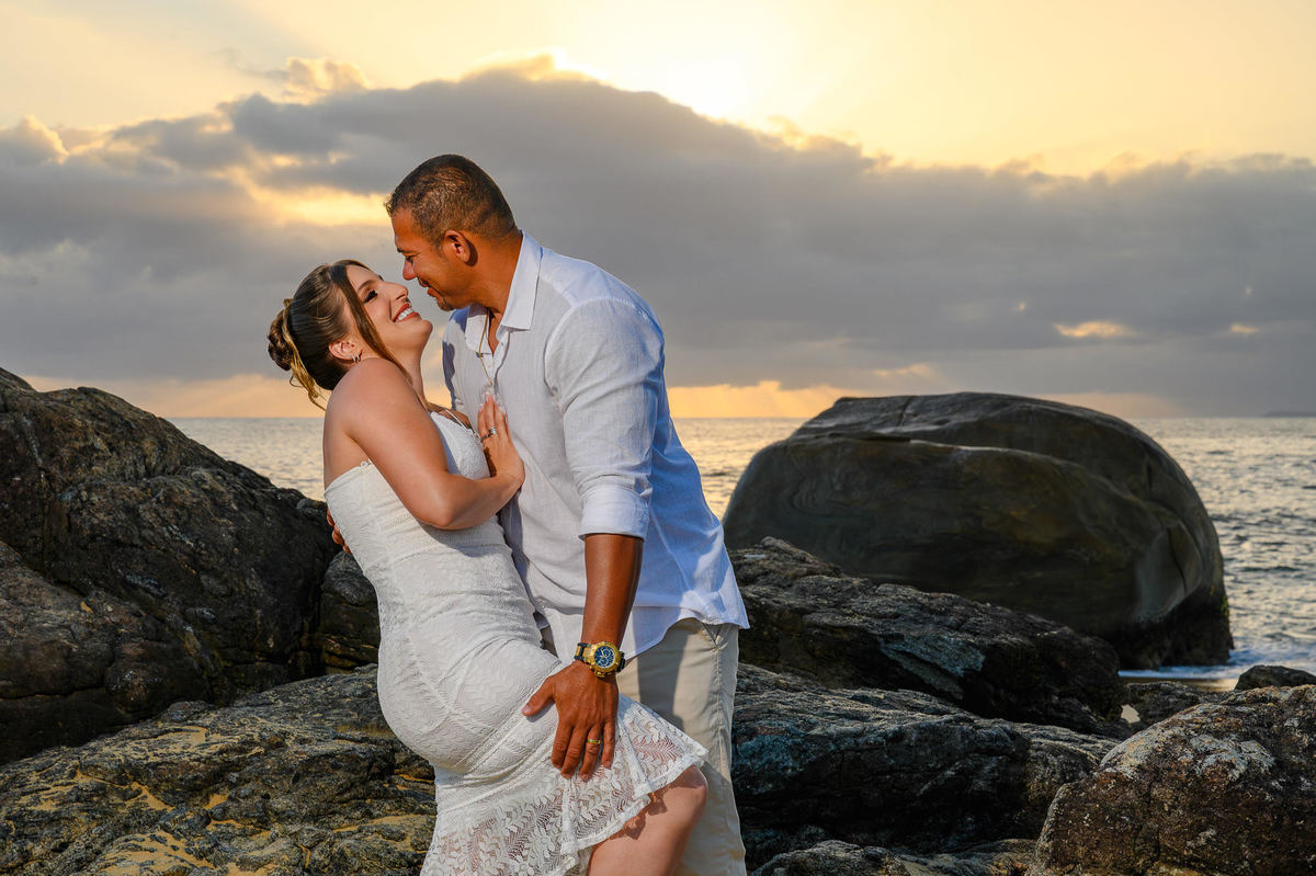 Casal se beijando nas rochas da praia do Estaleirinho ao amanhecer, ensaio fotográfico romântico em Santa Catarina