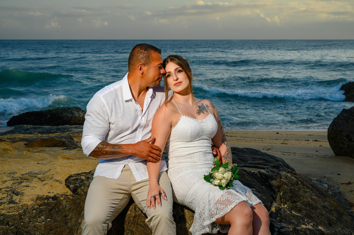 Casal sentado nas pedras com o mar ao fundo ao amanhecer, ensaio de casal na praia do Estaleirinho em Balneário Camboriú