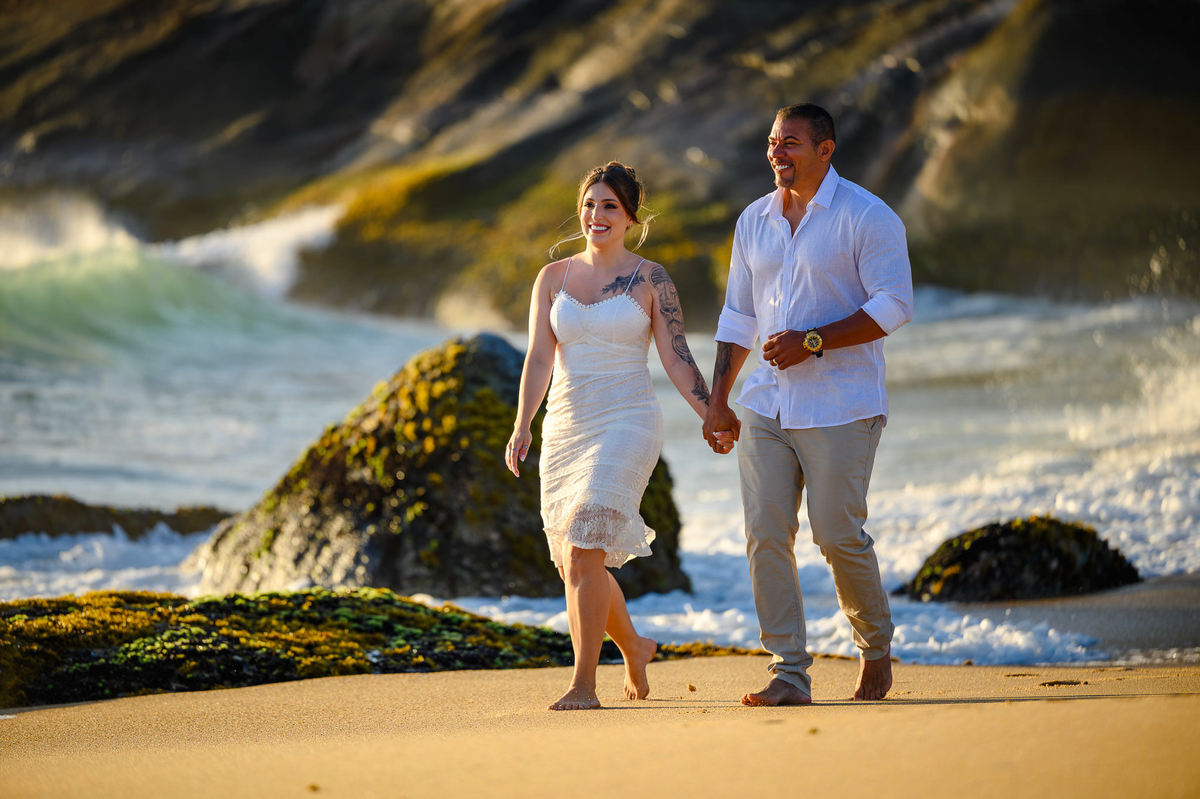 Casal caminhando de mãos dadas na areia ao amanhecer, ensaio fotográfico de casal na praia do Estaleirinho
