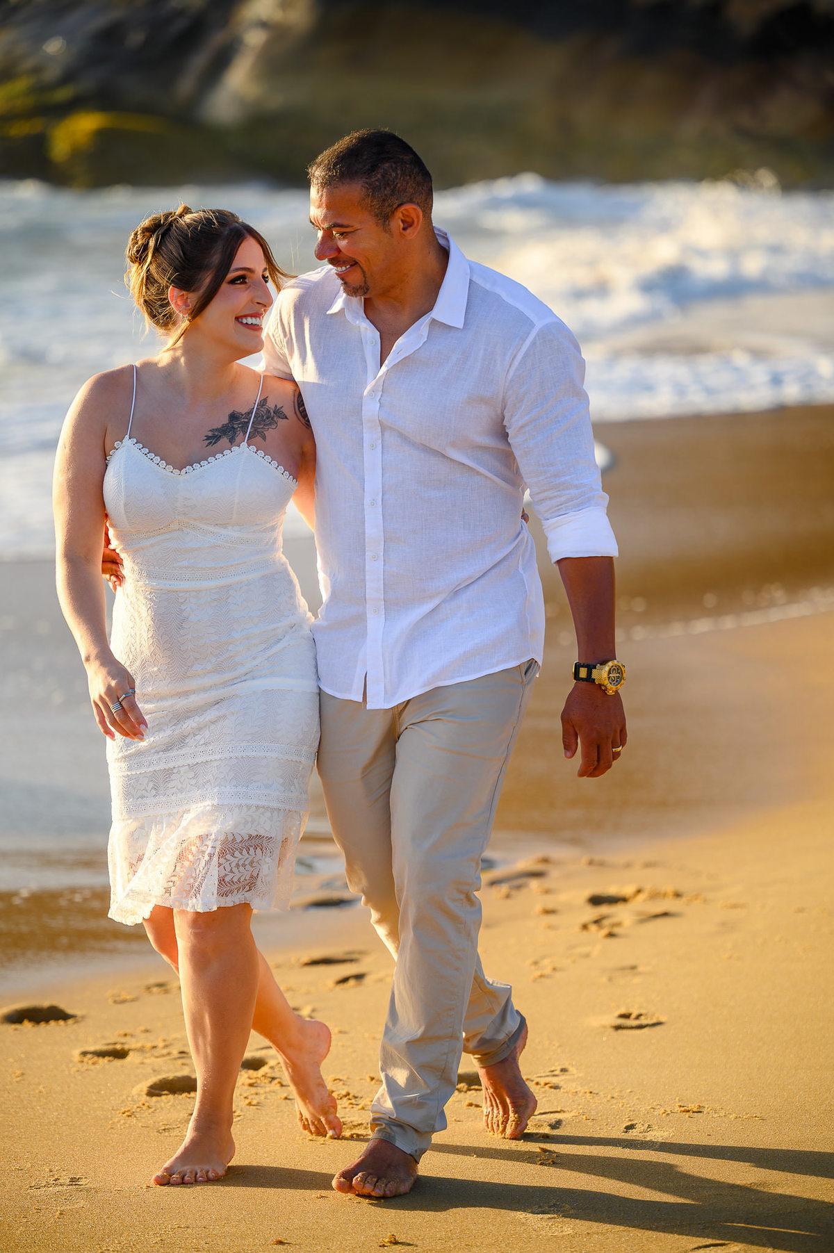 Casal caminhando de mãos dadas na areia ao amanhecer, ensaio fotográfico de casal na praia do Estaleirinho