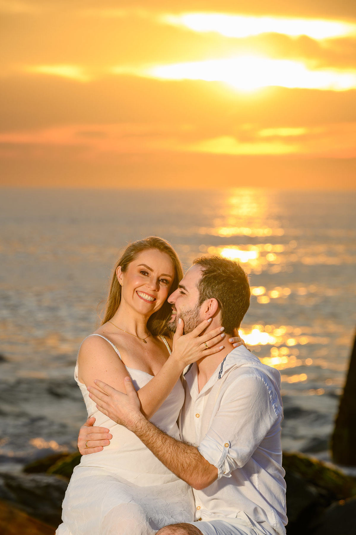 Close de casal em ensaio pré-wedding com reflexo do sol no mar na Praia do Estaleirinho, SC