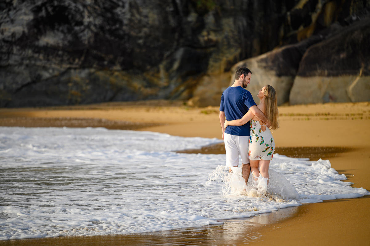 Casal caminhando na beira do mar durante ensaio pré-wedding no Estaleirinho
