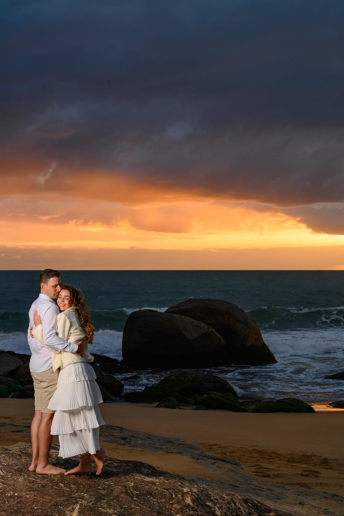 Retrato de casal em ensaio pré-wedding na Praia do Estaleirinho em Balneário Camboriú SC com céu dramático ao fundo