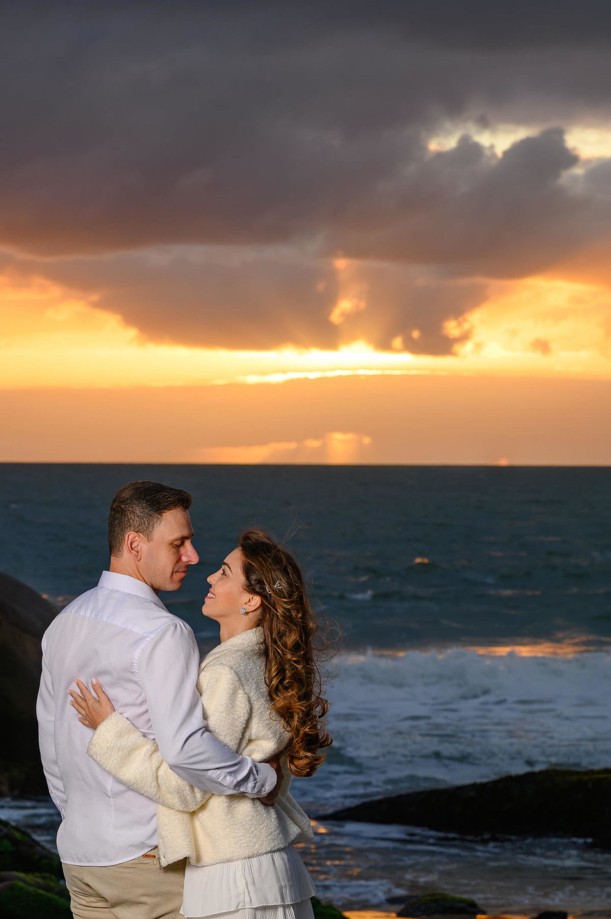 Retrato romântico de casal contra a luz do sol nascente na Praia do Estaleirinho em Balneário Camboriú SC