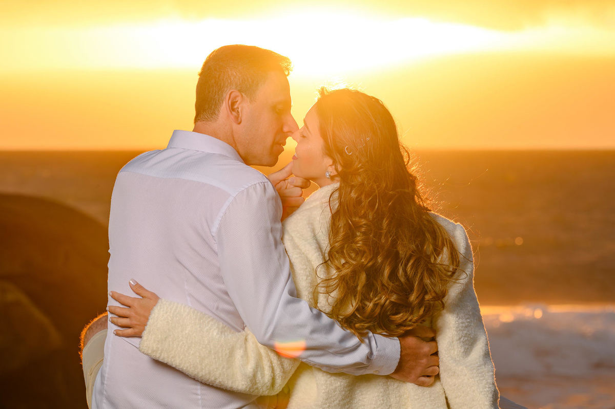 Ensaio de casal ao amanhecer em Balneário Camboriú SC com luz dourada do sol e mar ao fundo