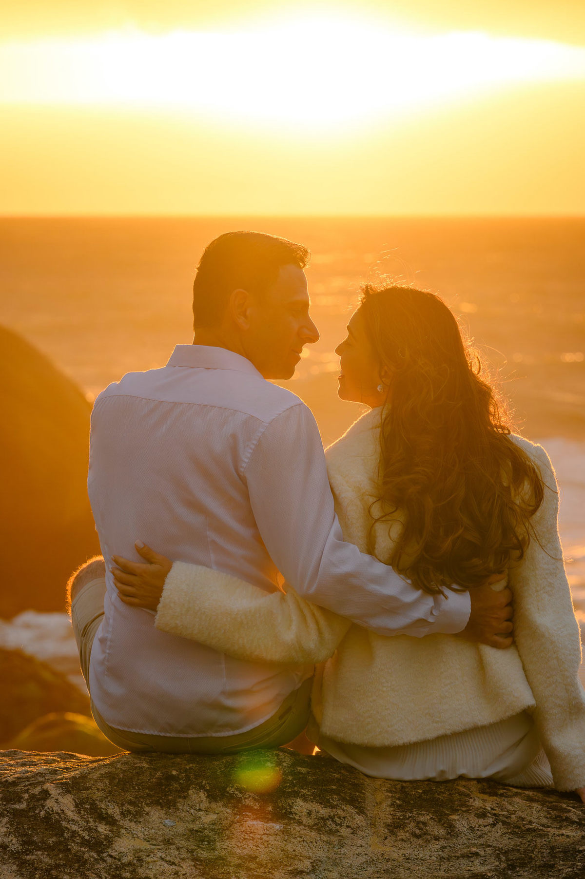 Ensaio de casal ao amanhecer em Balneário Camboriú SC com luz dourada do sol e mar ao fundo