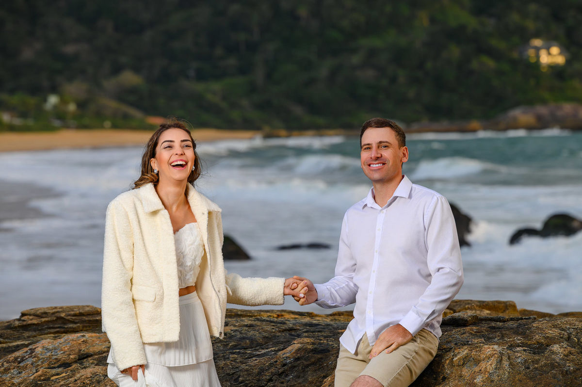 Retrato de casal em ensaio fotográfico de casal na praia em Balneário Camboriú SC com pedras e ondas ao fundo