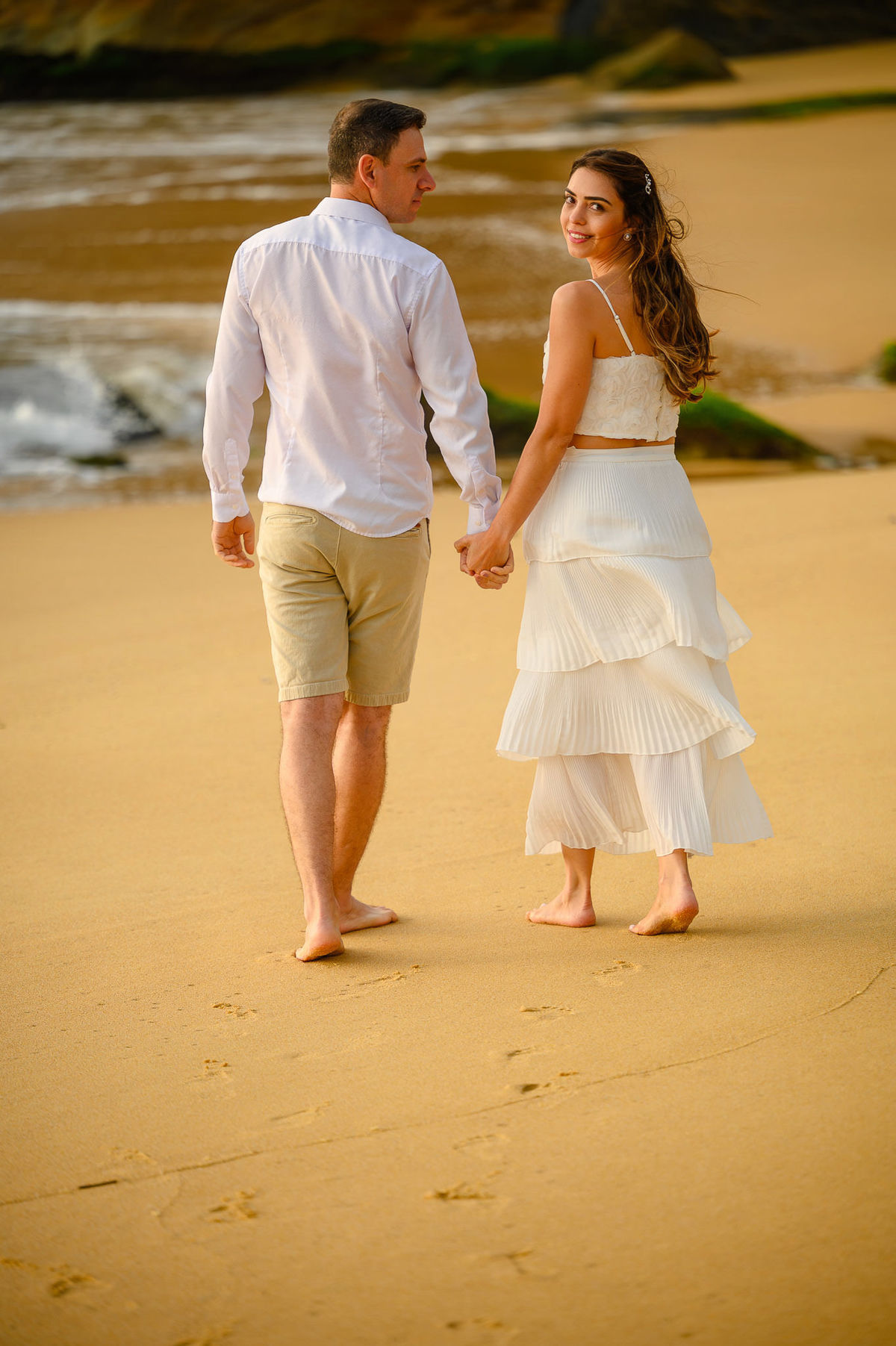 Casal caminhando de mãos dadas na areia durante ensaio pré-wedding ao amanhecer na Praia do Estaleirinho em Balneário Camboriú SC