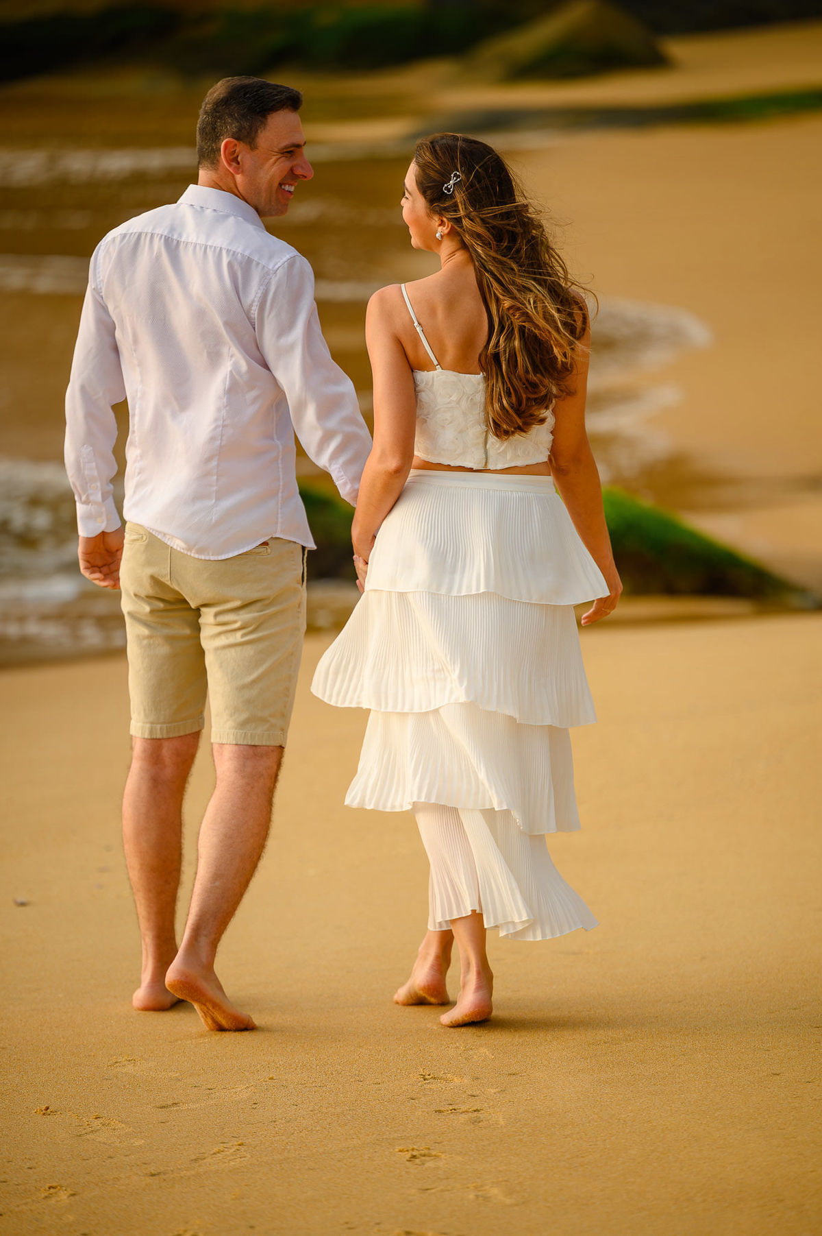 Casal caminhando de mãos dadas na areia durante ensaio pré-wedding ao amanhecer na Praia do Estaleirinho em Balneário Camboriú SC