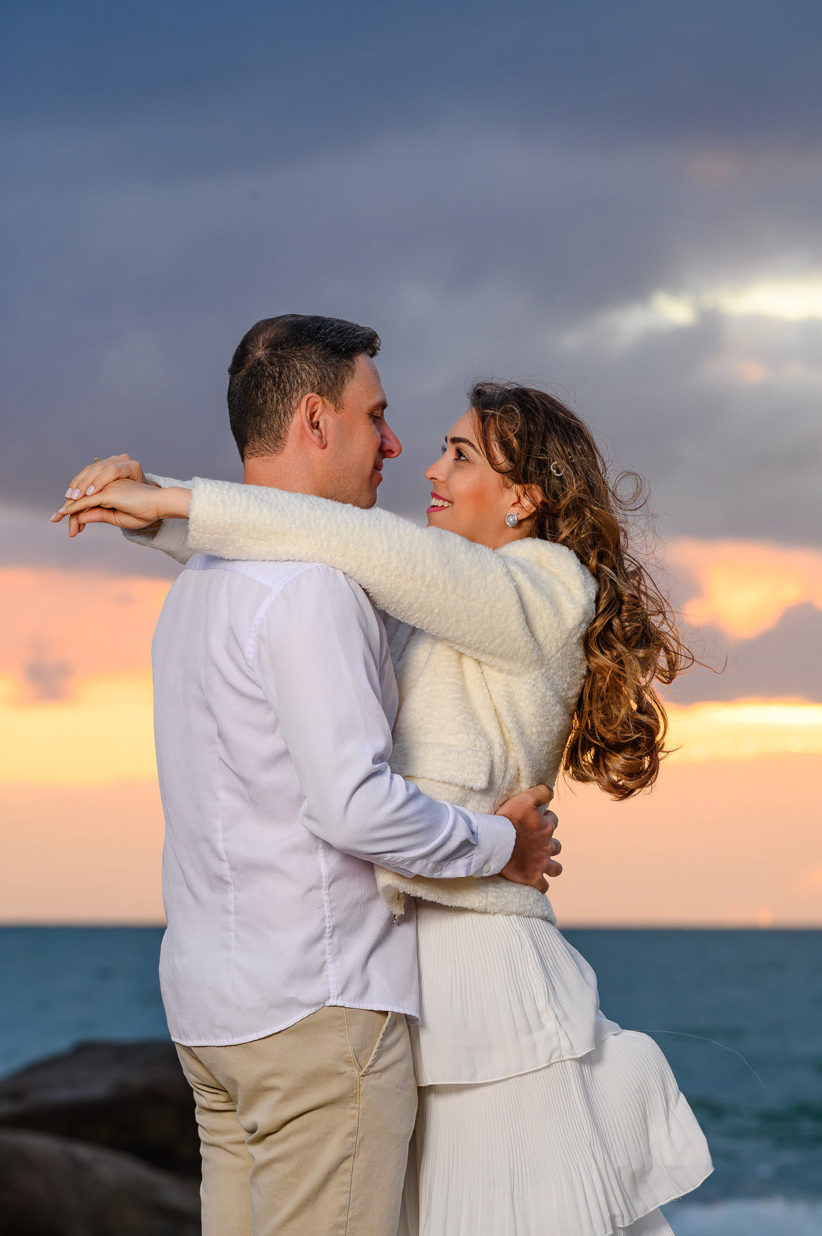 Retrato de casal em ensaio pré-wedding na Praia do Estaleirinho em Balneário Camboriú SC com céu dramático ao fundo