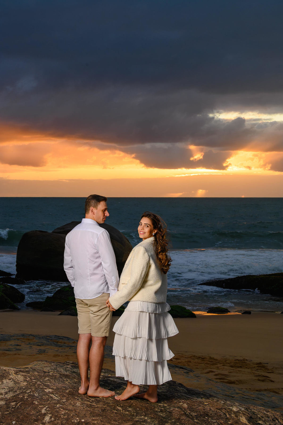 Retrato de casal em ensaio pré-wedding na Praia do Estaleirinho em Balneário Camboriú SC com céu dramático ao fundo