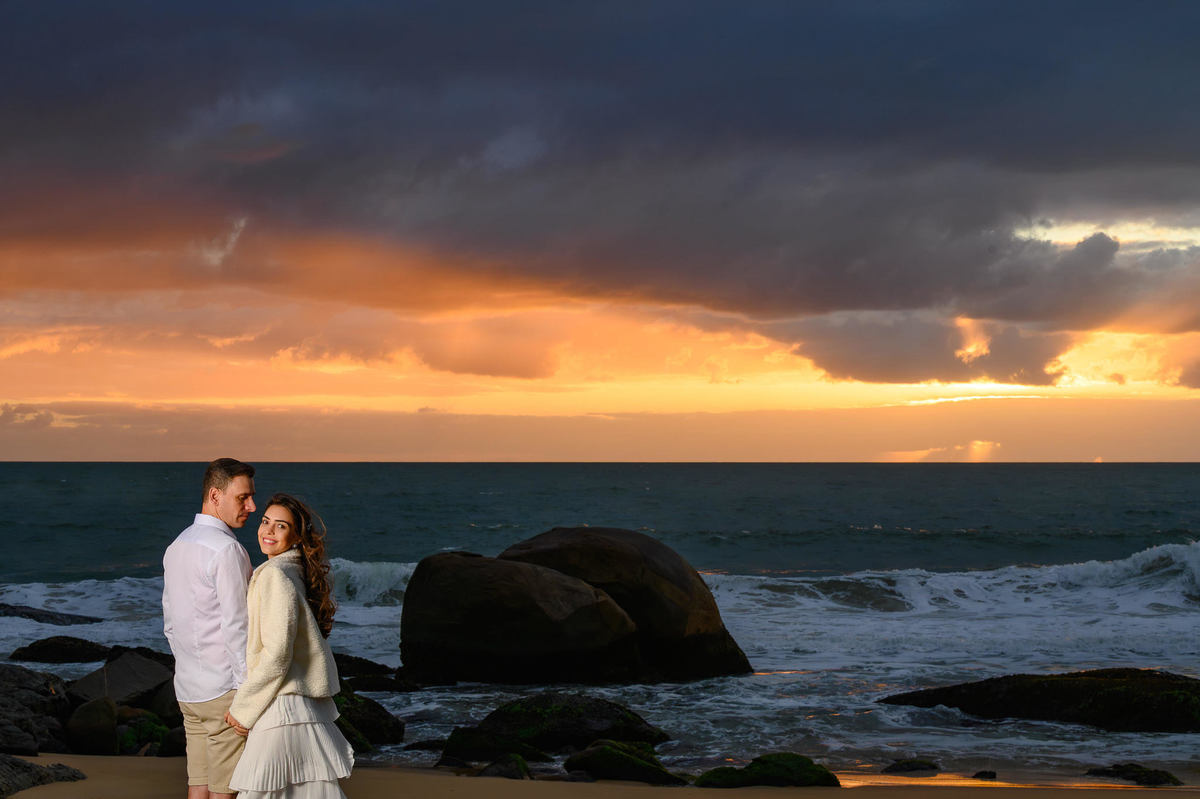 Retrato de casal em ensaio pré-wedding na Praia do Estaleirinho em Balneário Camboriú SC com céu dramático ao fundo
