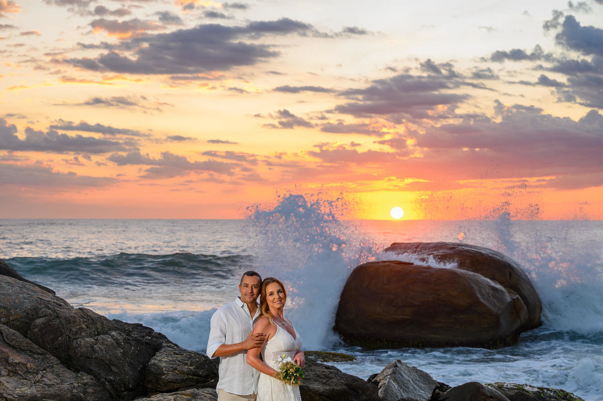 Ensaio fotográfico de casal na praia com ondas quebrando nas pedras em SC