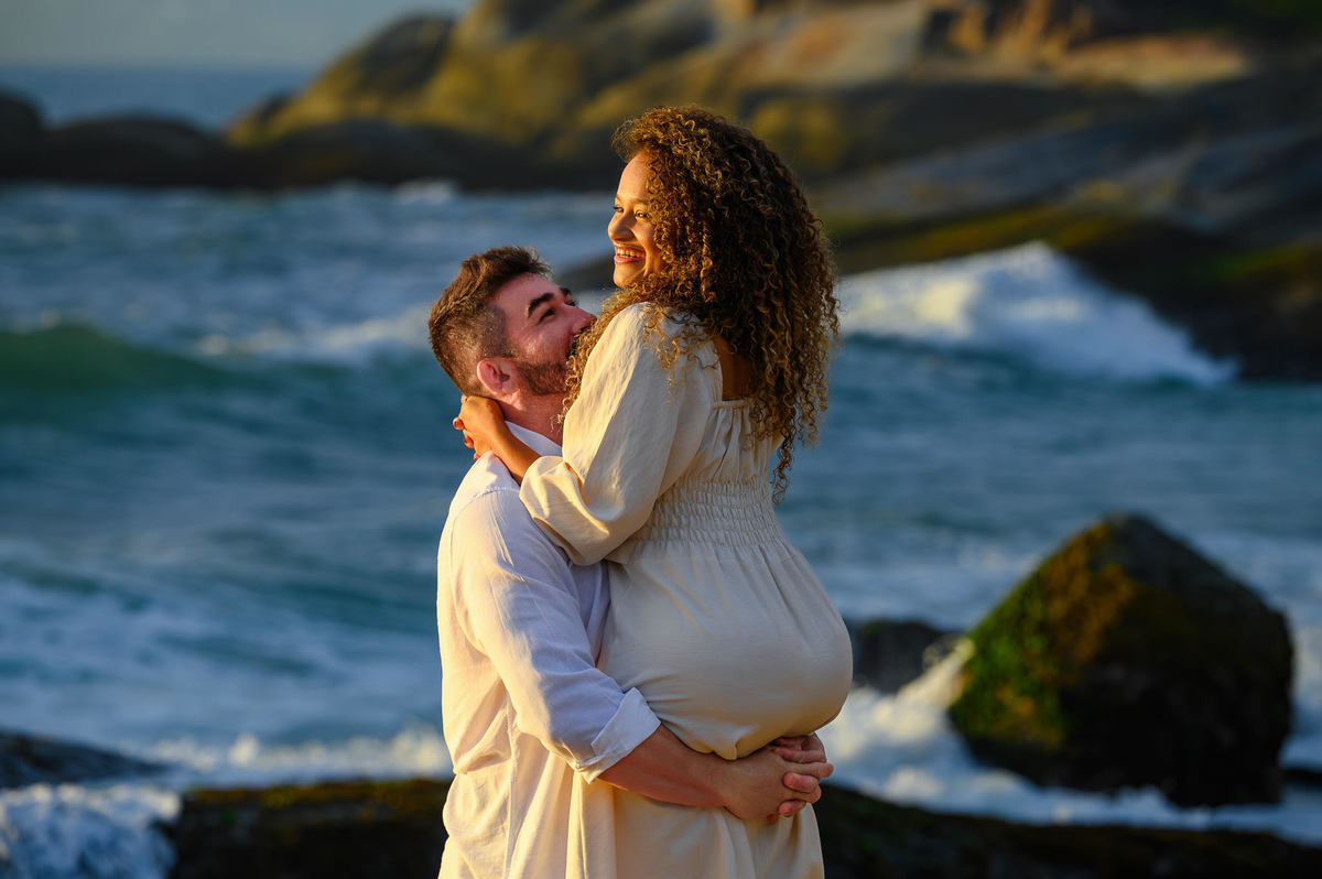 Casal girando e brincando durante ensaio pré-wedding ao amanhecer na Praia do Estaleirinho, Balneário Camboriú, com o mar ao fundo.