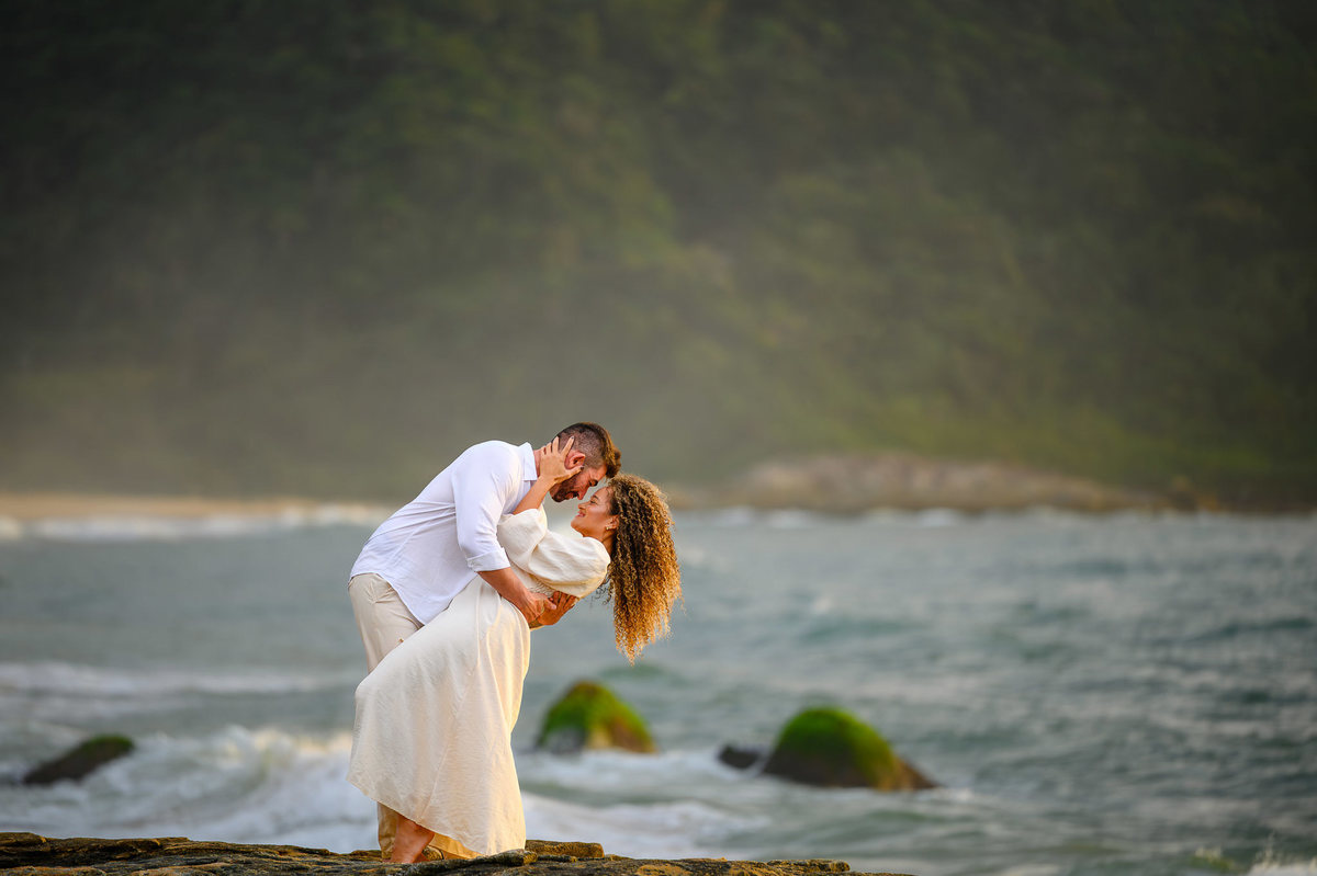Casal abraçado sobre as pedras na Praia do Estaleirinho durante ensaio pré-wedding ao amanhecer em Balneário Camboriú SC.