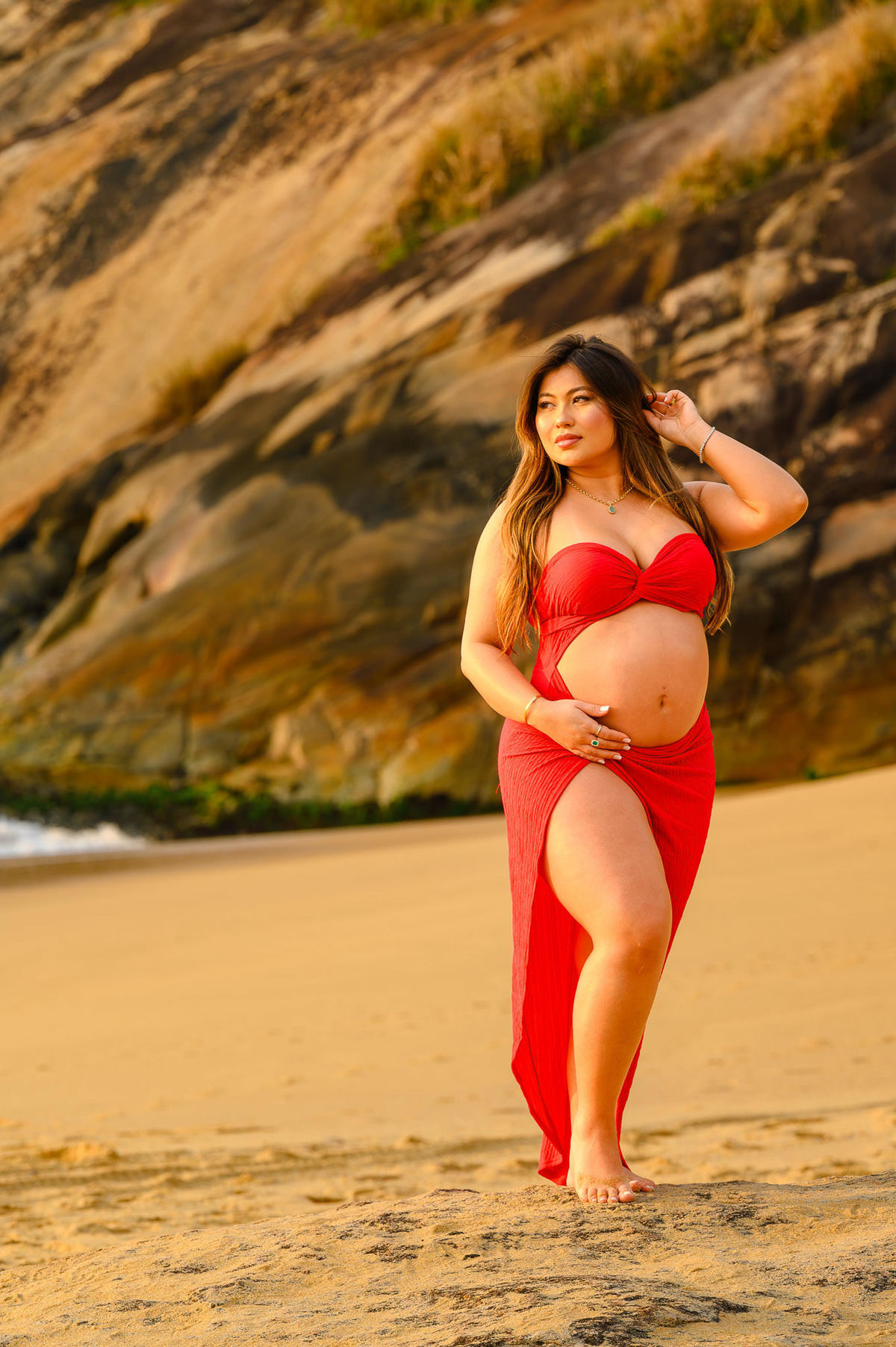 gestante bonita de roupa vermelha posando para fotógrafo em ensaio gestante na praia em santa catarina
