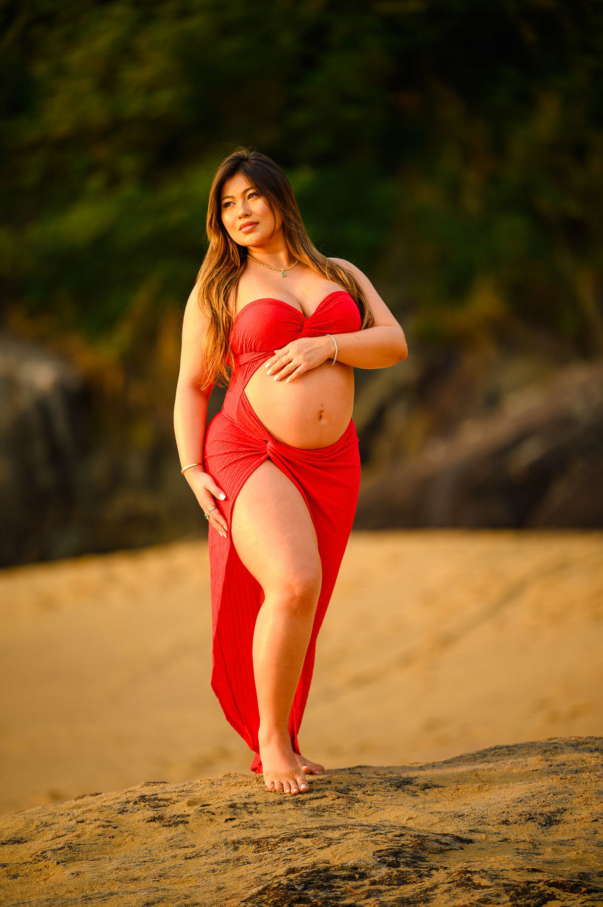 gestante bonita de roupa vermelha posando para fotógrafo em ensaio gestante na praia em santa catarina