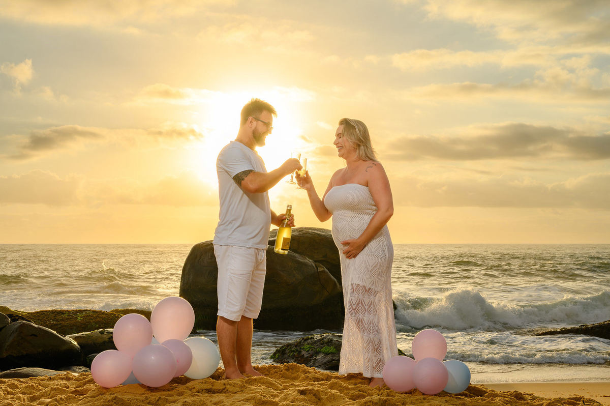 casal celebrando o chá de revelação na praia ao amanhecer em Balneário Camboriú SC