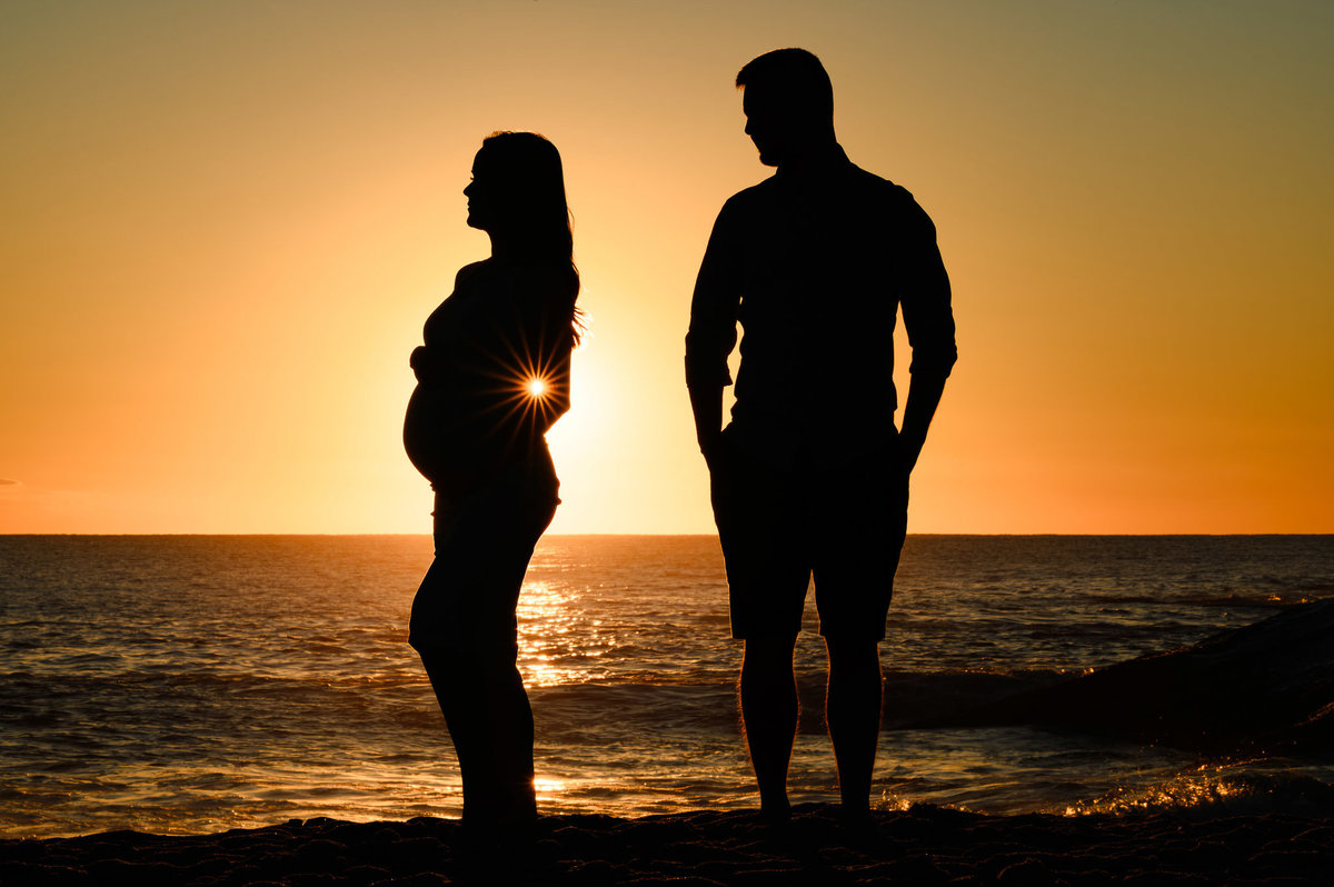 Silhueta de casal em ensaio gestante ao amanhecer na praia em Balneário Camboriú SC