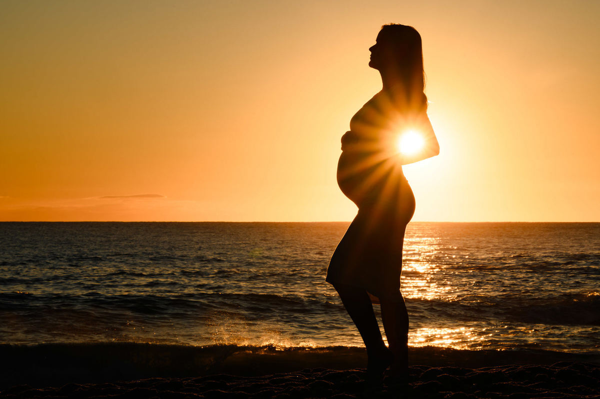 Silhueta de gestante ao amanhecer na praia em Balneário Camboriú SC