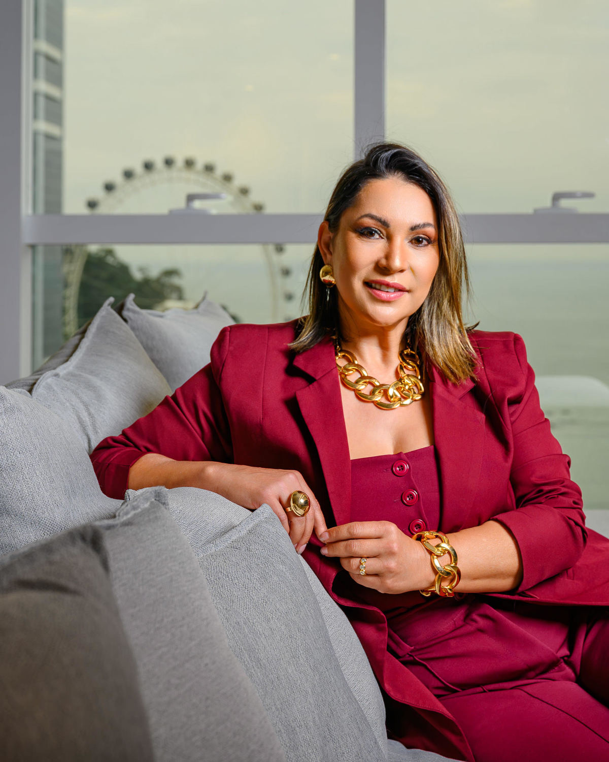 Retrato profissional de corretora em pose confiante dentro de apartamento com vista para ponto turístico de Balneário Camboriú.