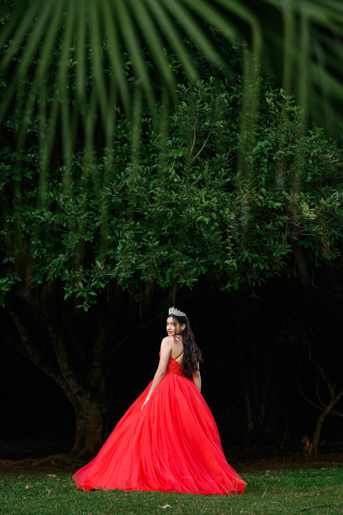 Ensaio de 15 anos em Balneário Camboriú com debutante usando vestido vermelho no Parque Raimundo Malta