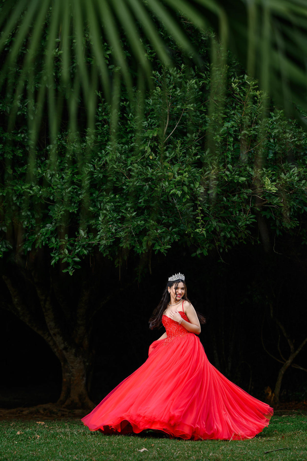 Ensaio de 15 anos em Balneário Camboriú com debutante usando vestido vermelho no Parque Raimundo Malta