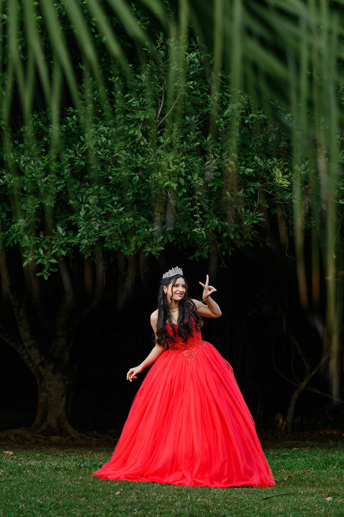 Ensaio de 15 anos em Balneário Camboriú com debutante usando vestido vermelho no Parque Raimundo Malta