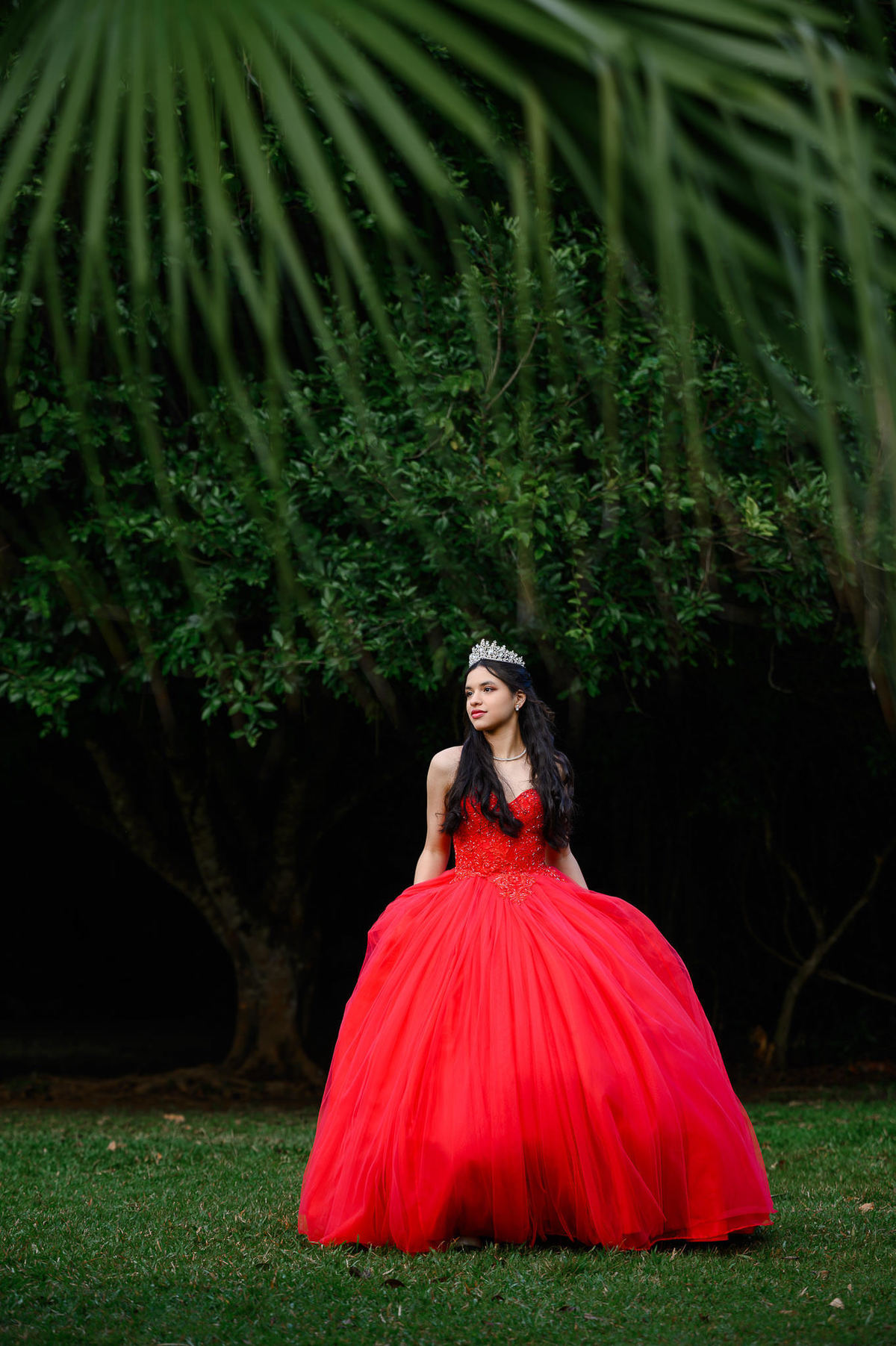Ensaio de 15 anos em Balneário Camboriú com debutante usando vestido vermelho no Parque Raimundo Malta